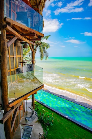 A wooden structure with a glass balcony overlooking turquoise ocean waves.