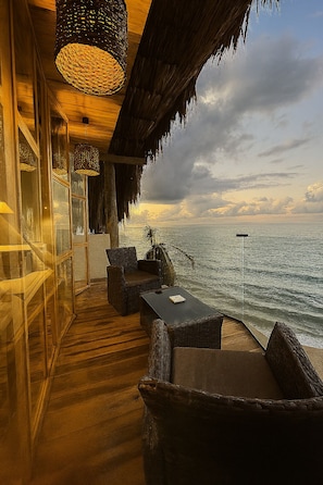 A coastal room with wicker furniture, a wooden floor, and a view of the sea.