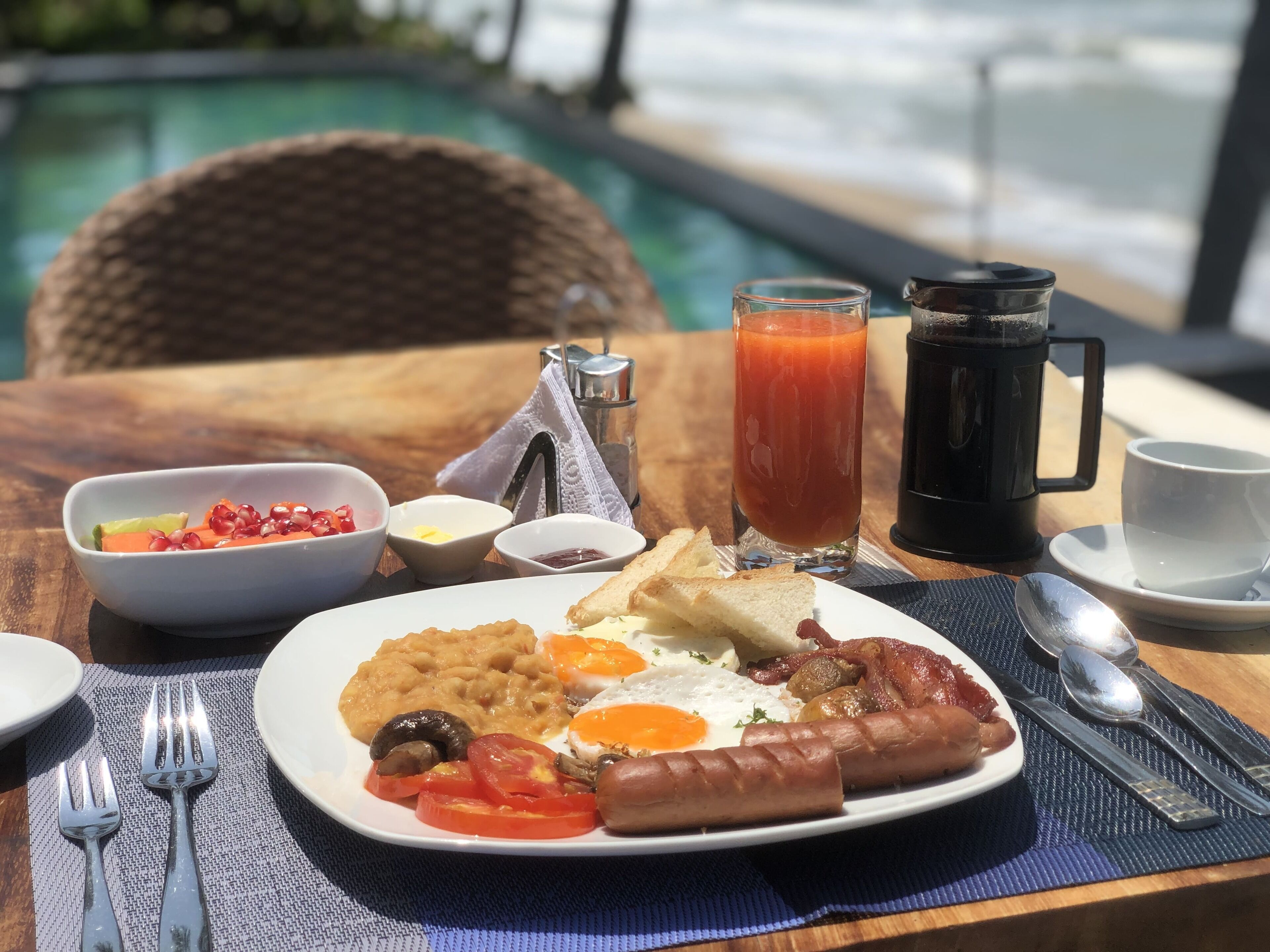 Un plato de desayuno con huevos, salchichas, frijoles y tomates.