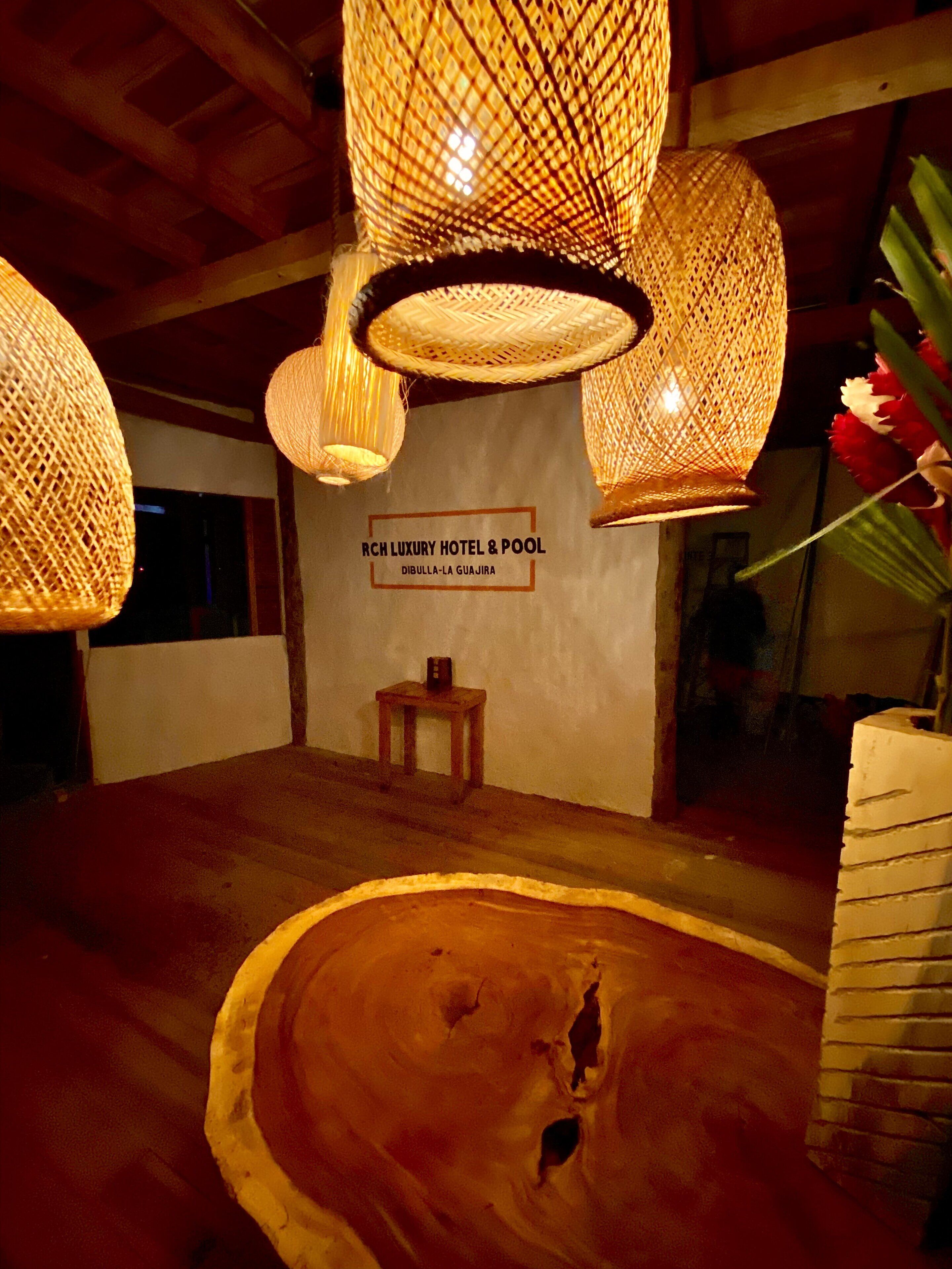 A room with a wooden floor, a sign for RCH Luxury Hotel & Pool, and a small wooden table.