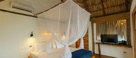 A bedroom with a bed, a TV, and a mosquito net.