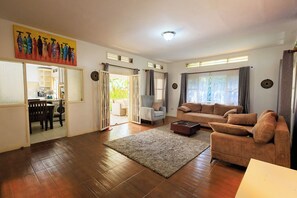 Ein Wohnzimmer mit einer Couch, einem Couchtisch und einem Teppich. Es gibt eine Essecke mit Tisch und Stühlen.