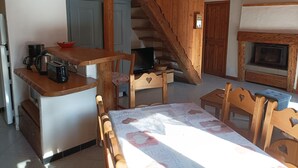 Tunnelmallinen keittiö, jossa on puuhuonekaluja, ruokapöytä ja takka.