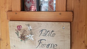 Puinen ovi, jossa on ikkuna ja kyltti, jossa lukee: ”Petite Ferme”.