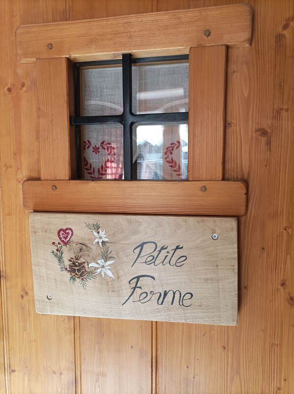 Une porte en bois avec une fenêtre et une enseigne sur laquelle on peut lire « Petite Ferme ».