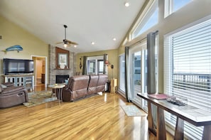 A spacious living room with a fireplace, leather sofa, and a flat-screen TV. - A Sunny Sandbar by Ryson Vacation Rentals (Galveston)