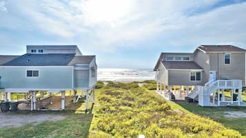 Two beachfront houses with elevated decks and a view of the ocean.