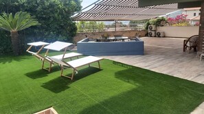 An outdoor patio with artificial grass, a fire pit, and lounge chairs. - Letter Luxury Apartment (Formia)