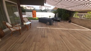 A patio area with wooden flooring, wicker chairs, a table, and a bar area. - Letter Luxury Apartment (Formia)