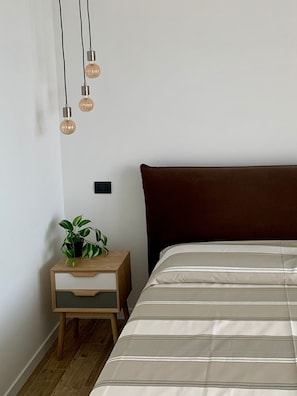 Un dormitorio con cama, mesita de noche y bombillas colgantes.