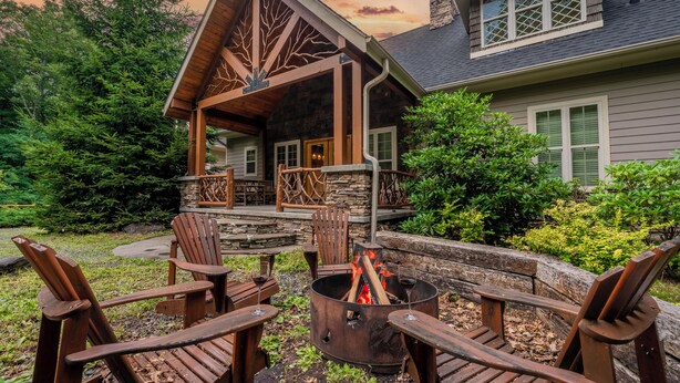 Eine Lodge mit Kamin aus Stein, einer Holzterrasse und Sitzgelegenheiten im Freien.