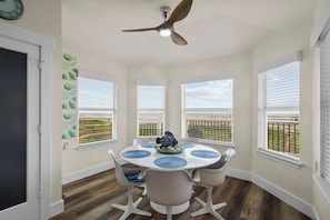 A dining area with a round table, white chairs, and a ceiling fan.