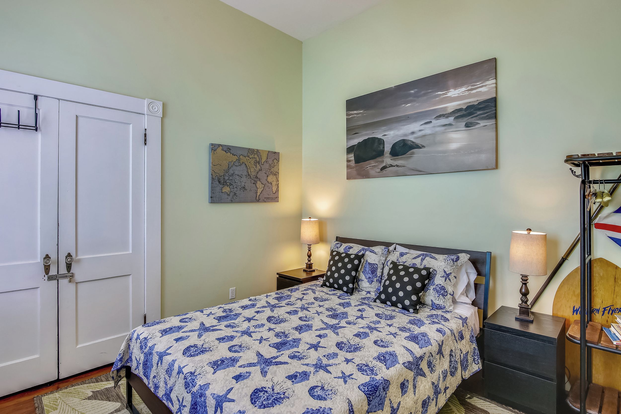 Une chambre à coucher avec un lit, deux tables de chevet, une carte et un tableau accroché au mur.