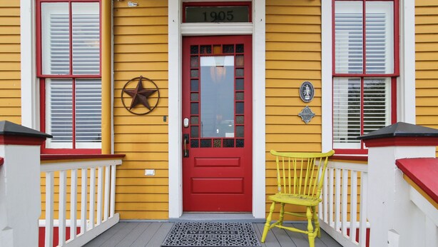 A yellow building with a red door, a star decoration, and a number '1905' above the door. - Abfab Seaside Cottage by Ryson Vacation Rentals (Galveston)