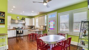 A kitchen with white cabinets, a stainless steel range, and a red dining set. - Abfab Seaside Cottage by Ryson Vacation Rentals (Galveston)