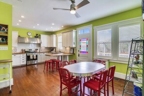 A kitchen with white cabinets, a stainless steel range, and a red dining set.