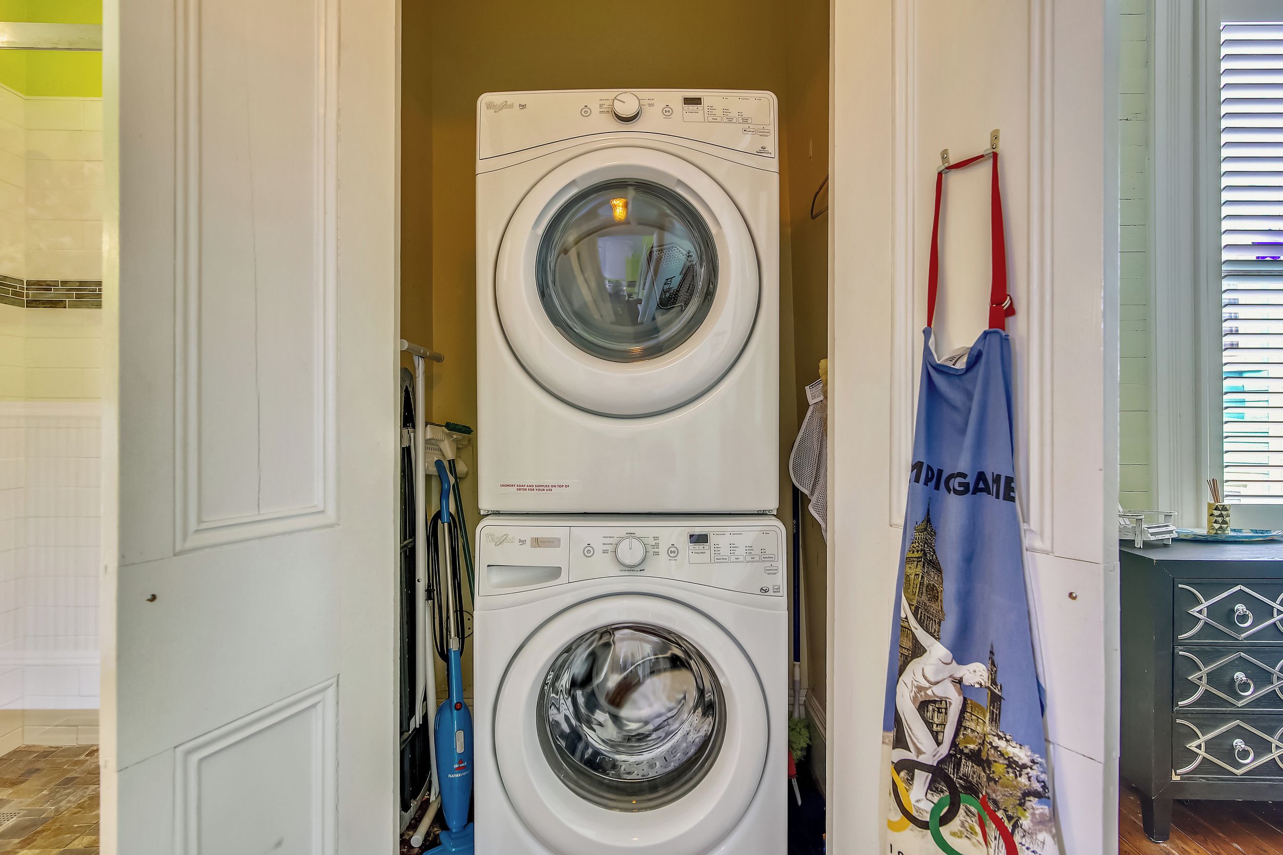 A stacked washer and dryer unit in a laundry room with a blue towel hanging nearby.