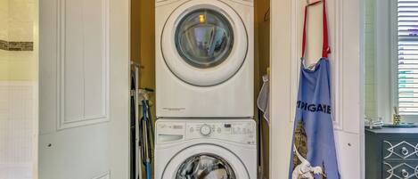 A stacked washer and dryer unit in a laundry room with a blue towel hanging nearby.