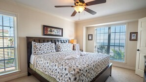A bedroom with a bed, a ceiling fan, a window, and a door. - Absolute Paradise-Dawn 1031 by Ryson Vacation Rentals (Galveston)