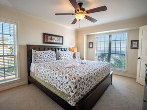 A bedroom with a bed, a ceiling fan, a window, and a door. - Absolute Paradise-Dawn 1031 by Ryson Vacation Rentals (Galveston)