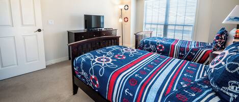 A bedroom with two beds, a dresser, a TV, and a window with blinds.