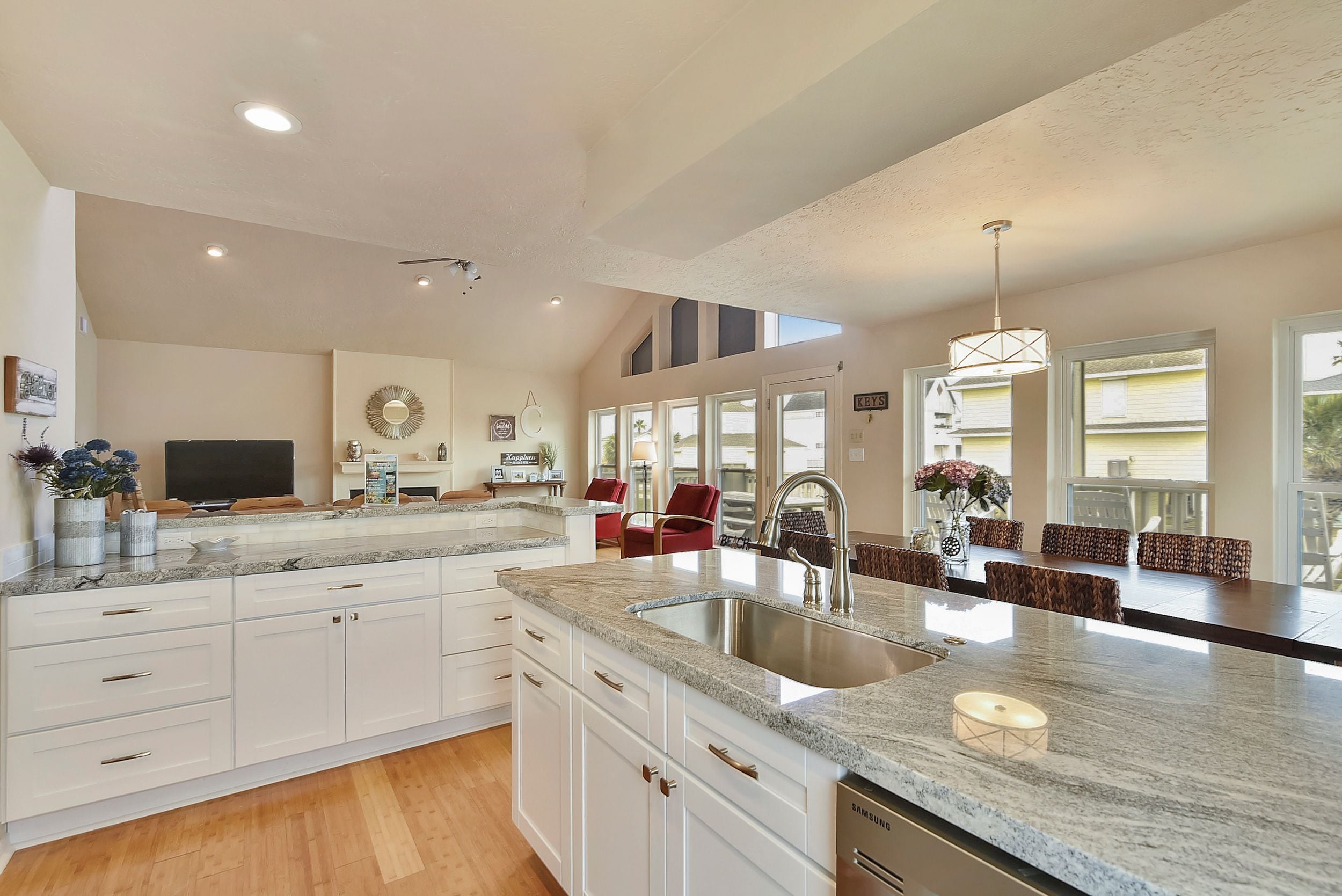 A spacious kitchen with a large island, white cabinetry, and a built-in sink.