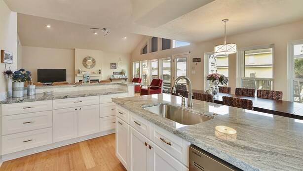 A spacious kitchen with a large island, white cabinetry, and a built-in sink. - All Decked Out by Ryson Vacation Rentals (Galveston)