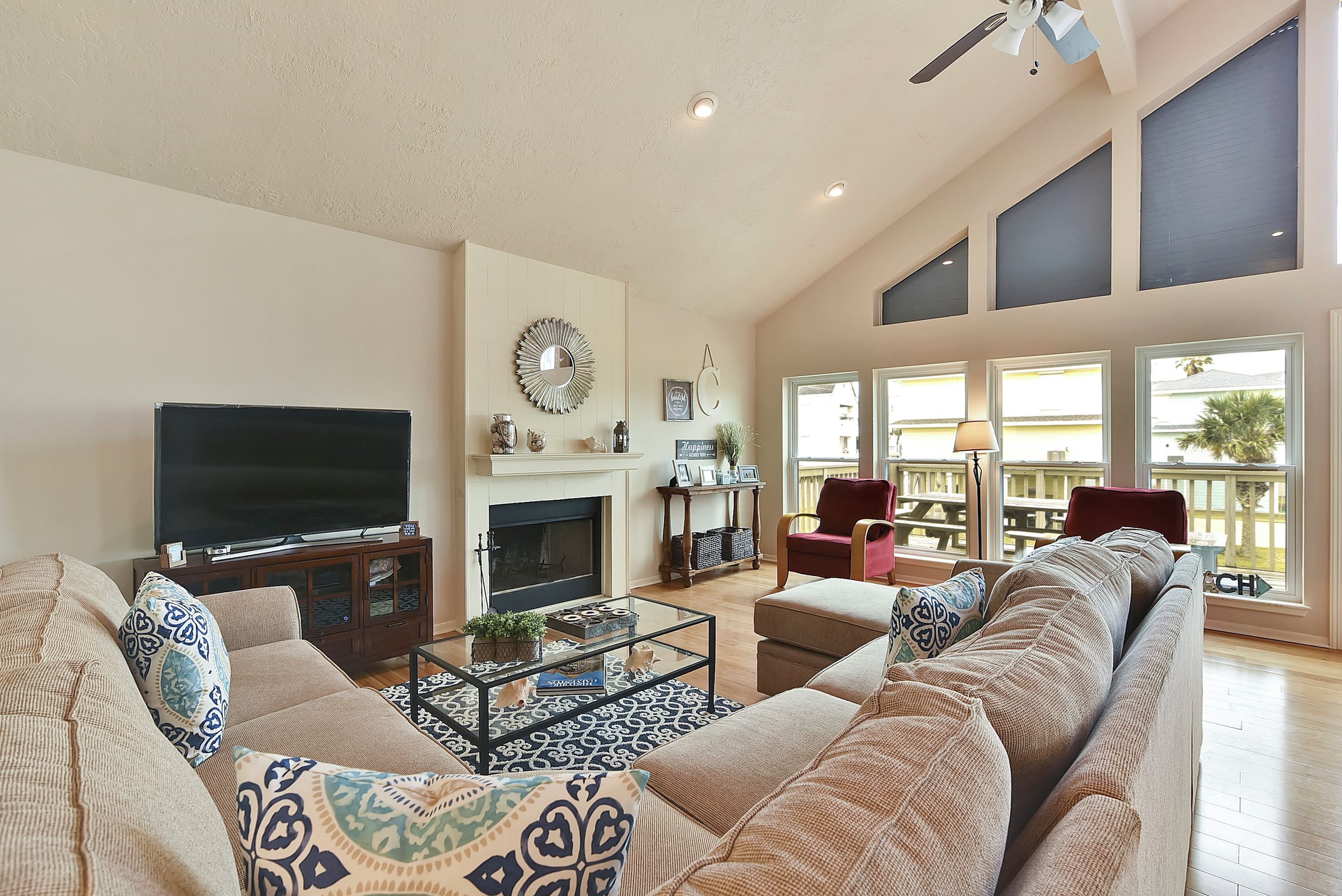 A spacious living room with a fireplace, large windows, and a television.