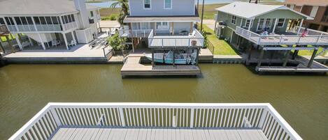 A waterfront property with a dock, a covered boat launch, and a house with a balcony.