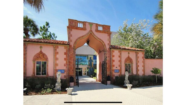 A building entrance with a pink facade, arched doorway, and two statues on either side. - Sarasota-Indian Beach Zen Home (private-pet friendly)  (Sarasota)