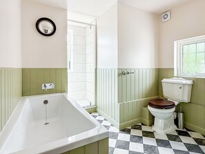 A bathroom with a bathtub, toilet, and a mirror on the wall.