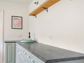 Une cuisine avec un plan de travail en granit, une bouteille de vin et des verres disposés sur un plateau turquoise.