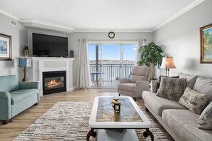 Een woonkamer met een open haard, een bank, een salontafel en uitzicht op het landschap.