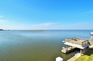 A waterfront property with a deck and outdoor seating area overlooking the water. - Bahia Azul Sunset by Ryson Vacation Rentals (Galveston)
