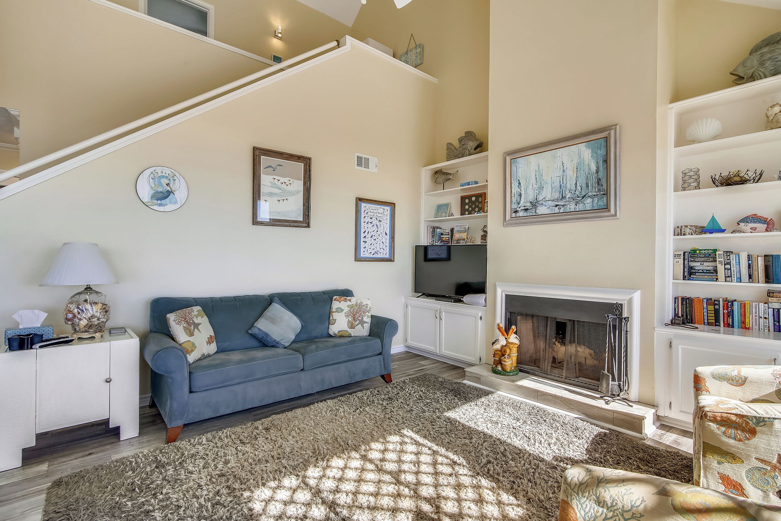 A living room with a blue sofa, a fireplace, and a bookshelf.