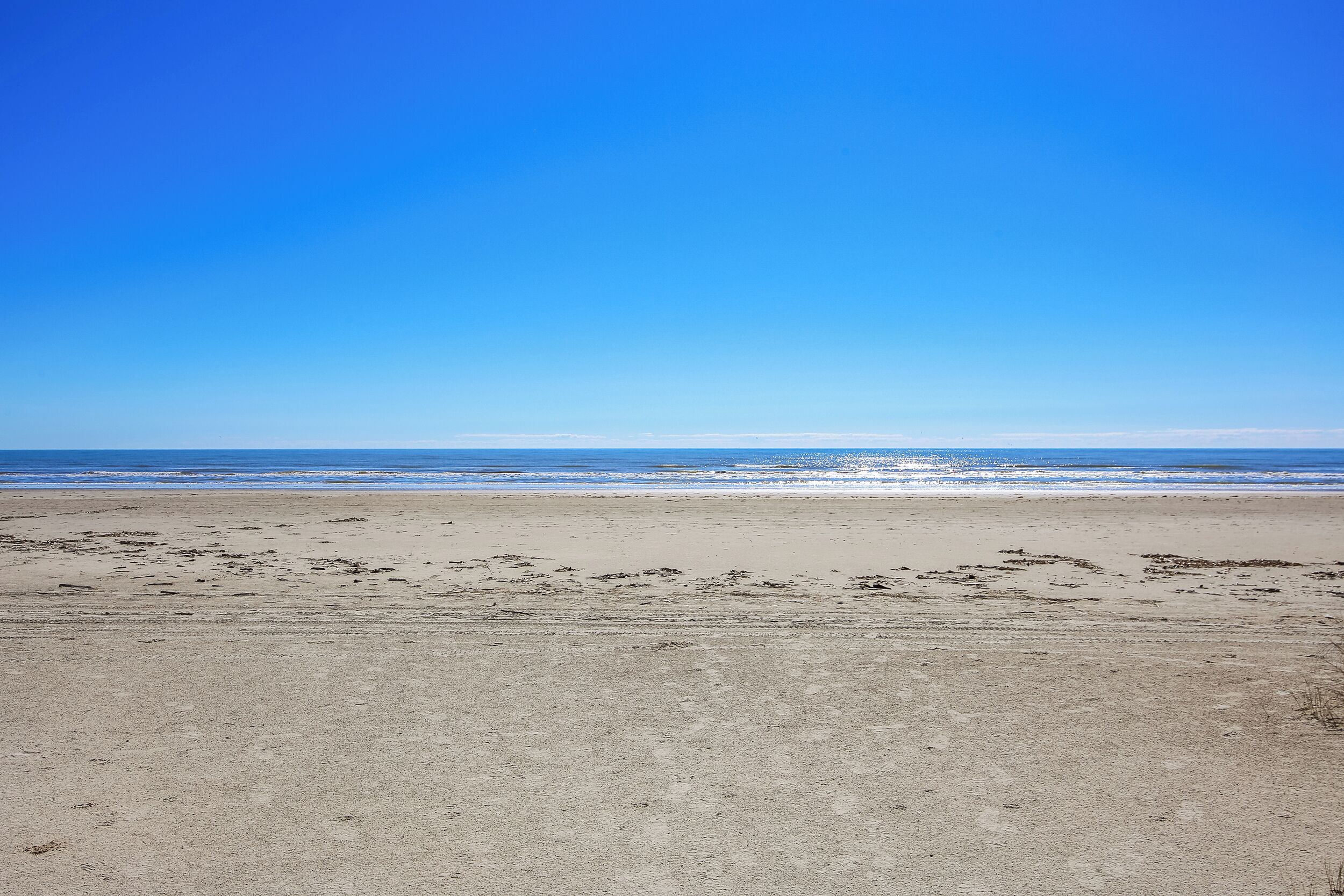 Ein Strand mit blauem Himmel und ruhiger See.