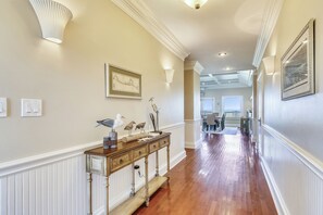 Stunning hallway with polished floors, console table, and artwork, leading to a dining area with a table and chairs.