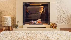 Ein Kamin mit Glasfront, eine Couch, eine Lampe und Dekorationselemente.