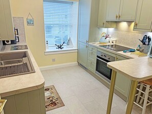 A kitchen with a window, a sink, a stove, and a countertop.