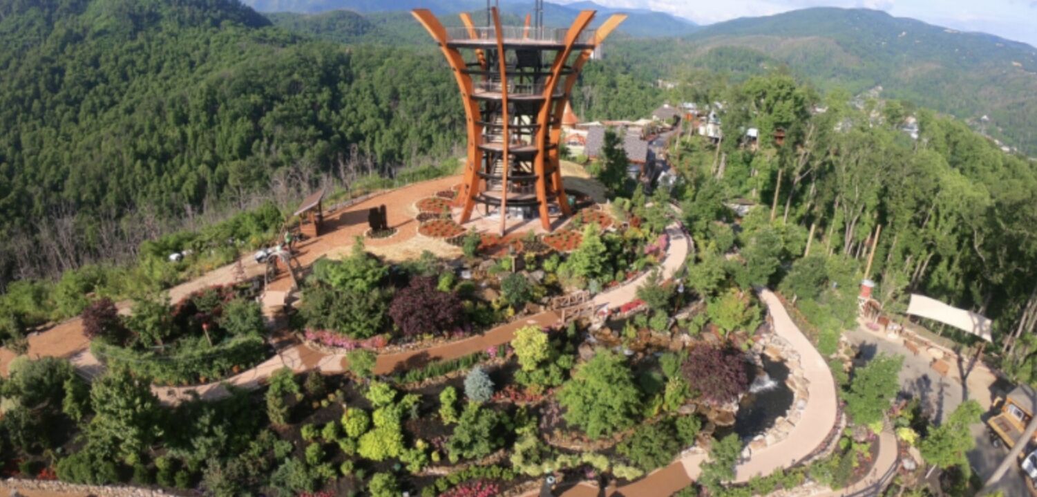 A large, modern tower structure surrounded by lush greenery and a winding path.
