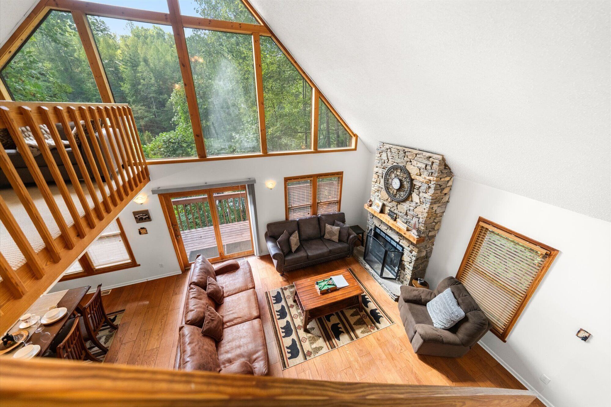 A spacious loft-style living area with a high ceiling, large windows, a fireplace, and a cozy seating arrangement.