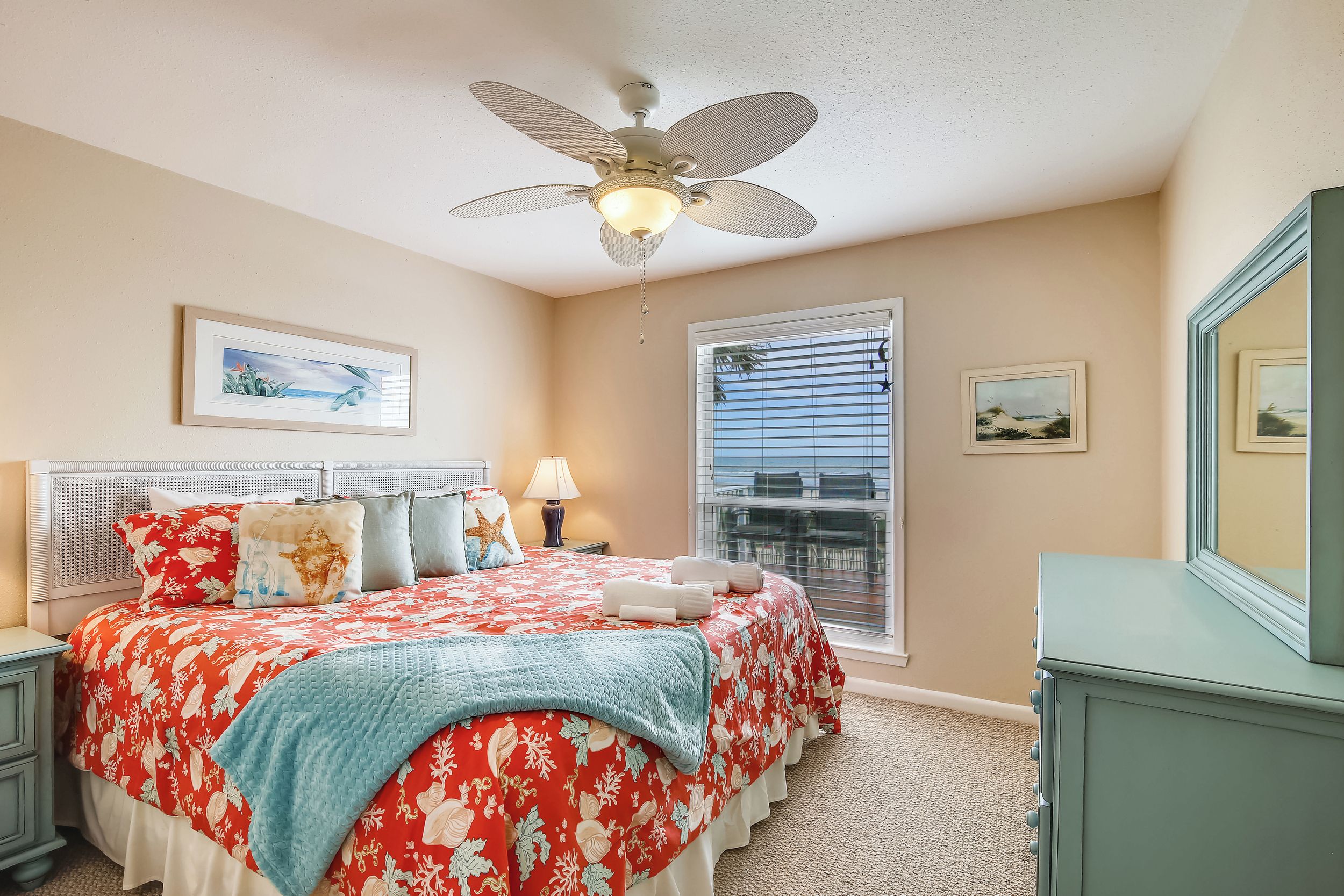 A bedroom with a bed, a nightstand, a dresser, a ceiling fan, and a window with blinds.