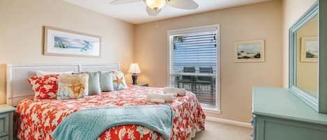 A bedroom with a bed, a nightstand, a dresser, a ceiling fan, and a window with blinds.