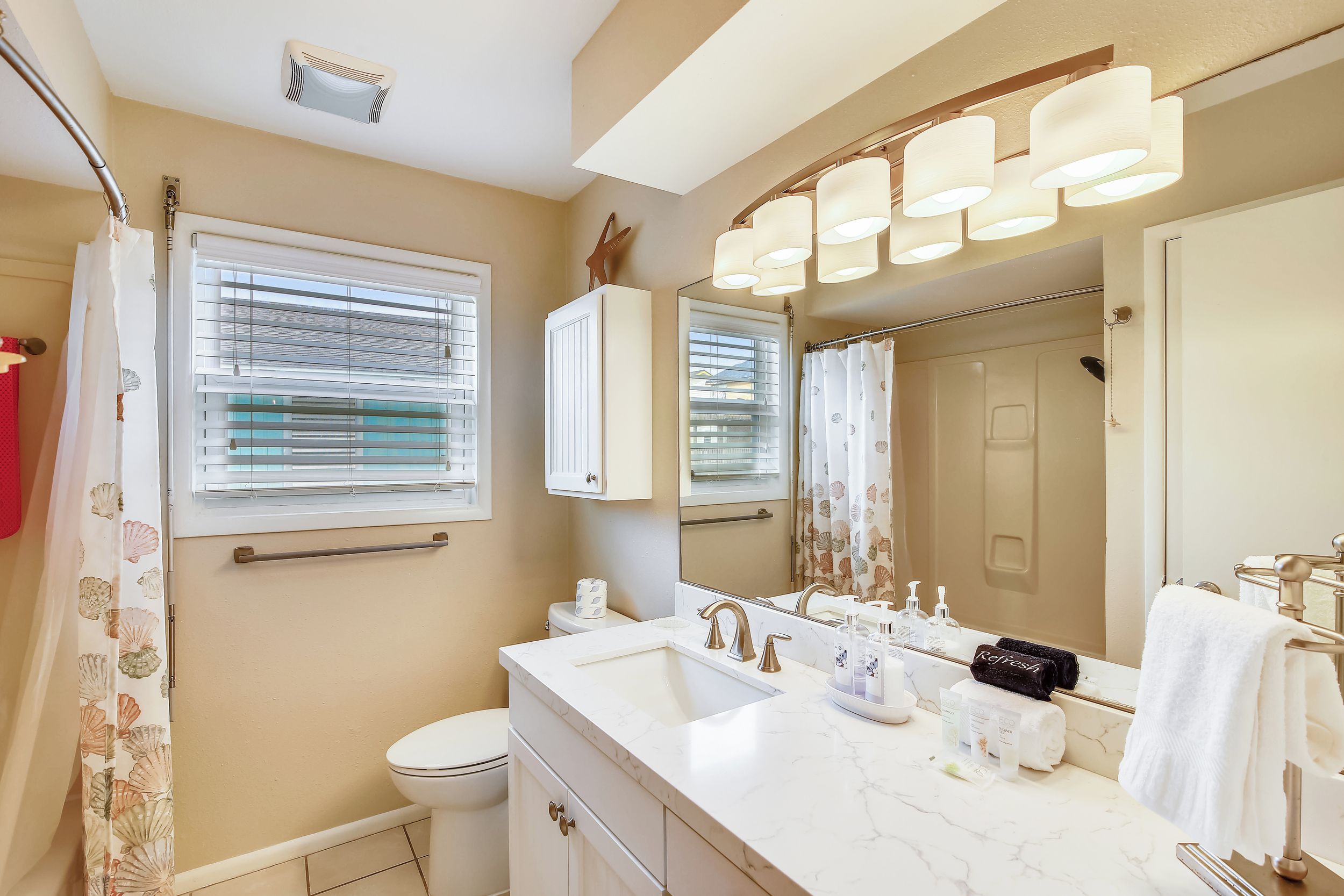 A bathroom with a white sink, a mirror, a toilet, and a shower curtain.