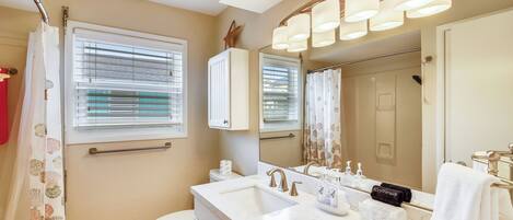 A bathroom with a white sink, a mirror, a toilet, and a shower curtain.