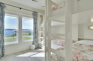 Una habitación con literas, una ventana con cortinas y vistas a edificios.