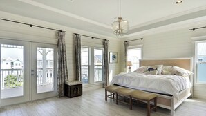 Un dormitorio con una cama grande, un banco, un aparador y vistas al balcón exterior.