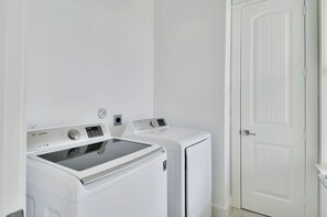 A laundry room with two white front-loading washing machines and a white door.