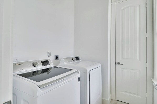 A laundry room with two white front-loading washing machines and a white door.