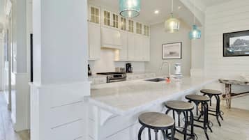 A modern kitchen with white cabinetry, a large island with bar stools, and pendant lighting.